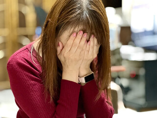 部屋で顔を覆って泣く女性