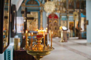 Naklejka premium burning candles in church. Christianity religious background. Orthodox christian church interior.