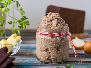 Appetizer, herring, onion and boiled egg forshmak in a glass jar on a wooden background. Jewish cuisine.