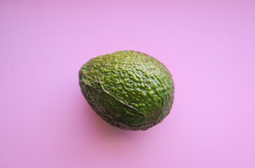 Single ripe avocado on a pink background