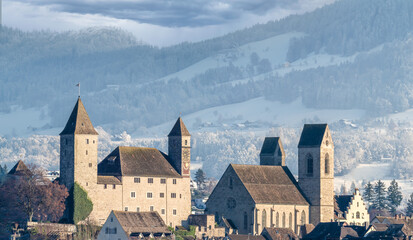 Fototapeta premium Stunning skyline of the iold city of Rapperswil St. Gallen with the snow covered mountains of the highlands of Zurich (Zürcher Oberland) in the background. Switzerland