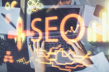 Double exposure of woman hands working on computer and seo hologram drawing. internet search...