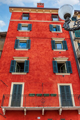 Colored facades of old buildings with balconies decorated with plants in the old part of Verona. Traditional Italian buildings