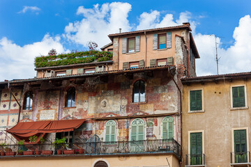 Colored facades of old buildings with balconies decorated with plants in the old part of Verona....