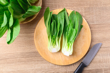Fresh Bok Choy or Pak Choi (Chinese cabbage) on cutting wooden board prepare for cooking, Table top view