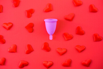 Fototapeta na wymiar Metaphor of female menstrual cup collecting menstruation blood, isolated on red background.