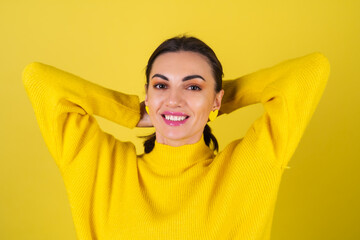 Young woman in a yellow cozy sweater on a background with bright pink glitter smiles sweetly, in a...