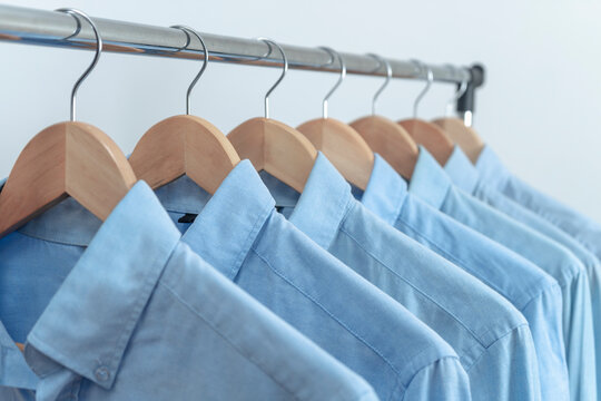 LIGHT BLUE SHIRTS HANGED IN THE CLOSET, DRESSING ROOM, BOUTIQUE OR STORE. MEN'S FASHION CONCEPT.