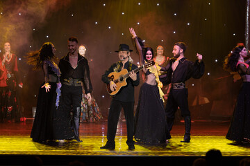 A team of musicians, singers and dancers in gypsy costumes singing and dancing on stage