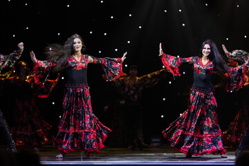 A team of musicians, singers and dancers in gypsy costumes singing and dancing on stage