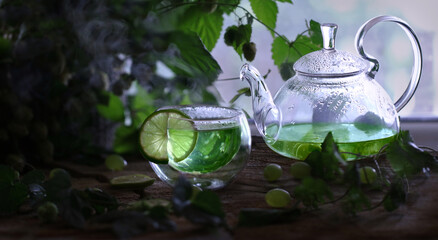 Atmospheric photo of a teapot and a mug with green tea on a wooden table