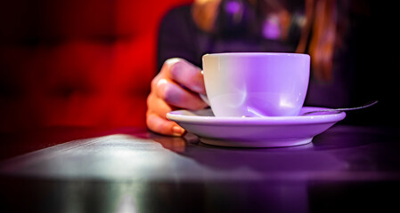 woman hands holding a white cup of tea or coffee standing on the table in cafe