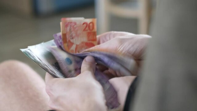 Men's hands count cash Philippine pesos and other currencies at home in a bright room
