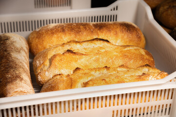 Fresh hot artisan bread in a white plastic transport box. Healthy and tasty food baked goods