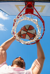 man dunking basketball ball through net ring with hands, success © Olena