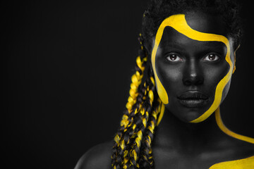 Yellow and black body paint. Woman with face art. Young girl with colorful bodypaint. An amazing afro american model with makeup. - obrazy, fototapety, plakaty