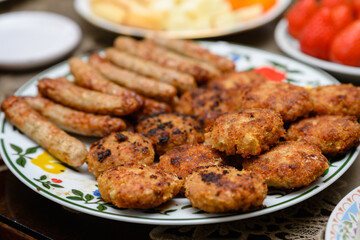 Fried meatballs and toasted mini sausages on a plate on the table.