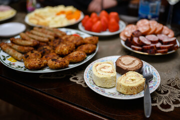 Sweet rolls and fried meatballs, toasted mini sausages, roller sausages on a plate on the table.