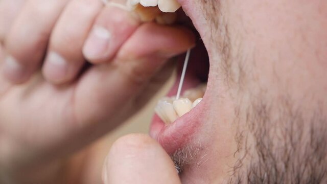 Daily health care. Man brushing teeth with dental floss