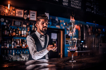 Charming barman demonstrates the process of making a cocktail behind bar