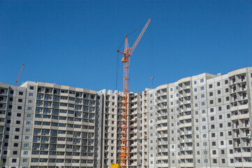 Fototapeta na wymiar Construction of high-rise houses and tall cranes