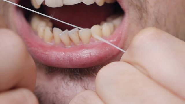 Daily health care. Man brushing teeth with dental floss