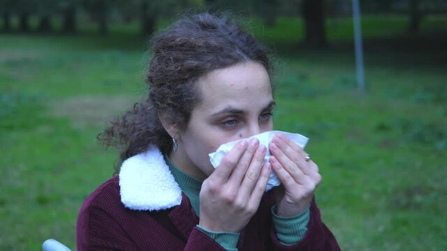 loneliness, disability-young woman with paraplegia alone at park blows her nose