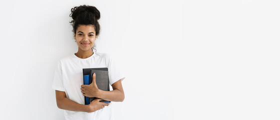 Young african american woman holding books and notepad in hands