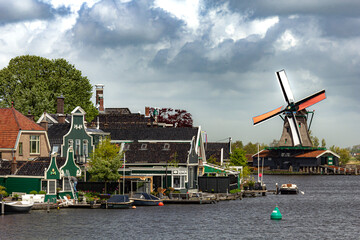 Fototapeta na wymiar Beautiful small houses by the water with windmills in Zaanse Schans, Netherlands