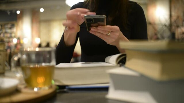A Woman Student Make Photo of Book Pages with Phone at the Cafe Table