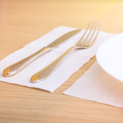 An empty plate, fork, knife, on a wooden table, side view.