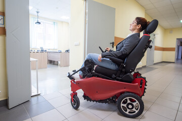 Caucasian woman in electric wheelchair in university corridor.