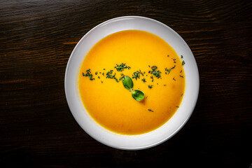 Pumpkin soup in white plate on black wooden table background