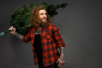 handsome man with long hair holding a synthetic christmas tree