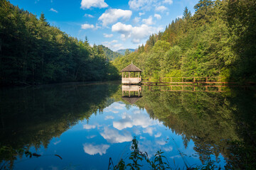 Cozy garden house on the lake in the mountains. Reflection of a beautiful sky in the water. Ukrainian Carpathians.