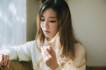 明るい窓辺で髪の毛を触る女性