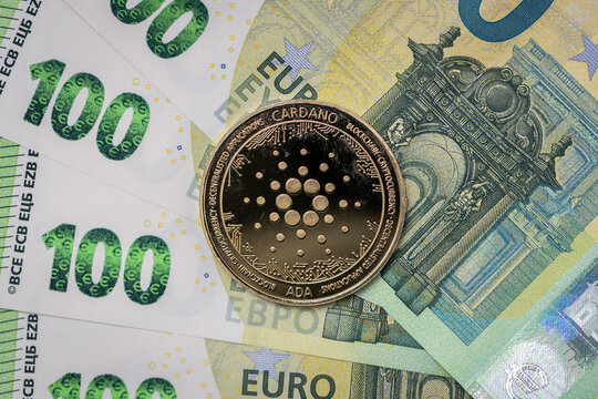 Cardano Ada physical coin laying on top of 100 Euro bills.