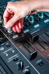 DJ Hands creating and regulating music on dj console mixer in concert nightclub