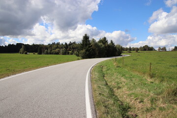 Fototapeta na wymiar A beautiful wide road in the landscape with blue sky and clouds above near Kaproun, Czech republic