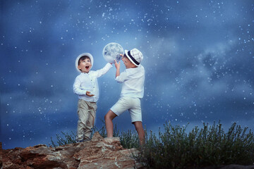 two children hang the moon into the star sky. 