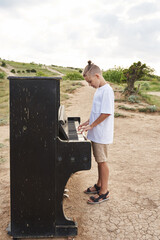 boy playing the old piano in the summer in the field