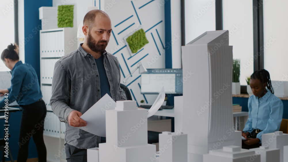 Poster portrait of engineer analyzing blueprints plan and building model to design architectural project. a