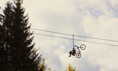 Bukovel, Ukraine. October 1, 2021. Sportsman tourist with a bicycle rides on chair lift cableway to...