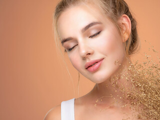 Naklejka premium Calm Blonde girl with a bunch spring dry field flowers near the face - over colored background. Beauty face care concept.
