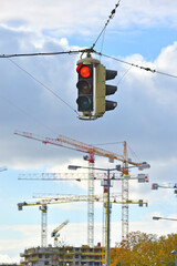 Baukräne auf einer Baustelle in Wien mit roter Ampel im Vordergrund