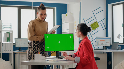Obraz premium Business people talking about green screen on monitor, using computer with isolated chroma key and mockup template. Women colleagues working with blank copy space background on display.