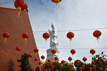 A Buddha statue in a Vietnamese temple against the sky, with red Chinese festive lanterns hanging in the foreground