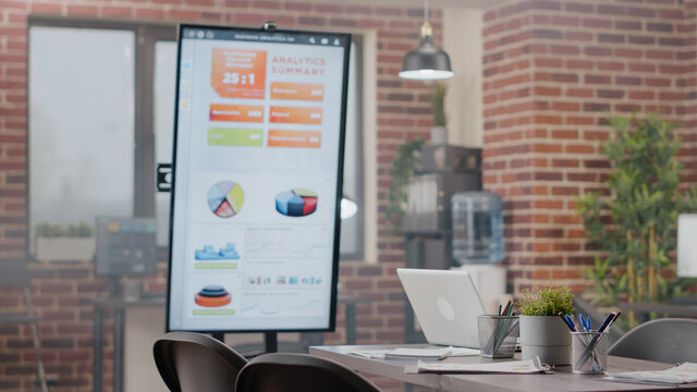 Close Up Of Empty Meeting Table In Business Office With Analysis Presentation On Monitor. Nobody In Startup Space Used For Research Work And Project Planning, No People At Company Job.