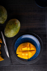 Ripe and tasty egyption Mango cubes and whole mango served at black table. flat lay