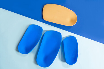 Foot support and healthy feet concept with orthopedic shoe insoles isolated on color background